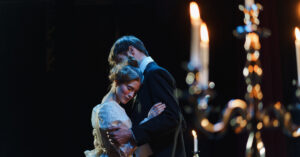 Two actors embracing on a contemporary theater stage.