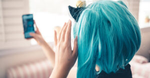 girl wearing a turquoise wig, taking a selfie.