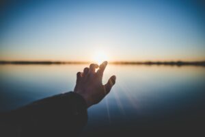 Hand reaching out to the horizon in hope