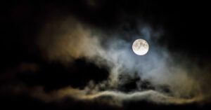 Midnight sky showing clouds and a full moon.