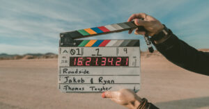 a person holding a film slate in a desert.