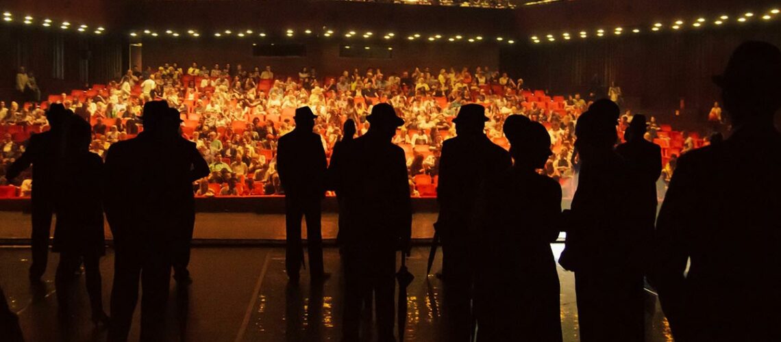 Actors performing on stage to an audience in a theatre production