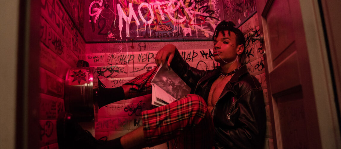 Individual in a leather jacket in a dimly lit room.