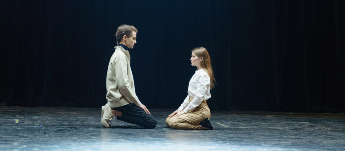Two people looking at one another on stage.