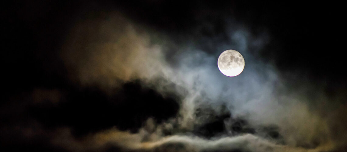 Midnight sky showing clouds and a full moon.