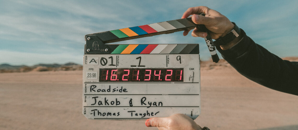 a person holding a film slate in a desert.