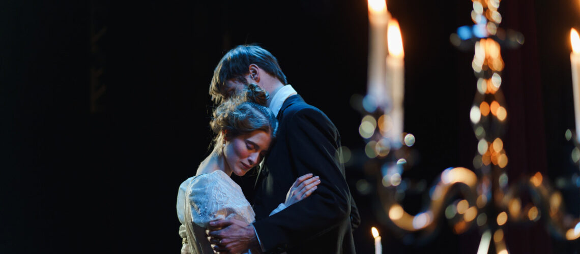 Two actors embracing on a contemporary theater stage.