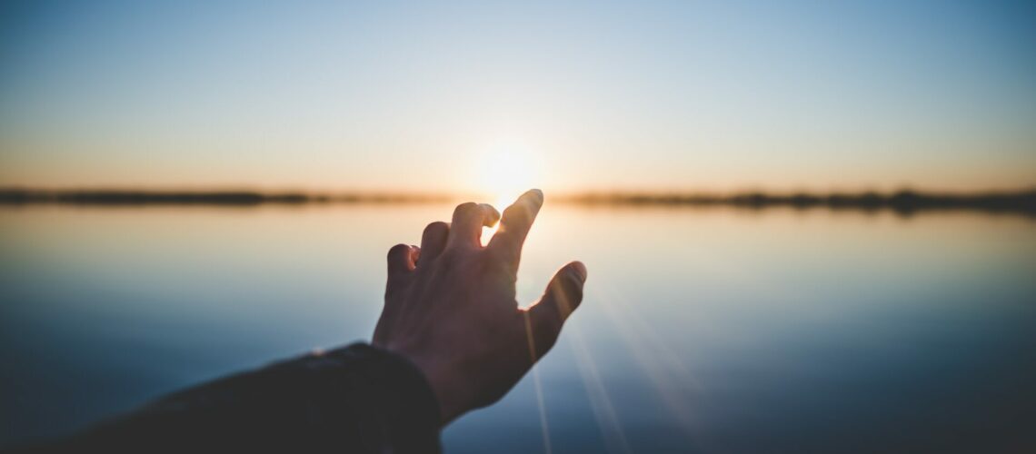 Hand reaching out to the horizon in hope
